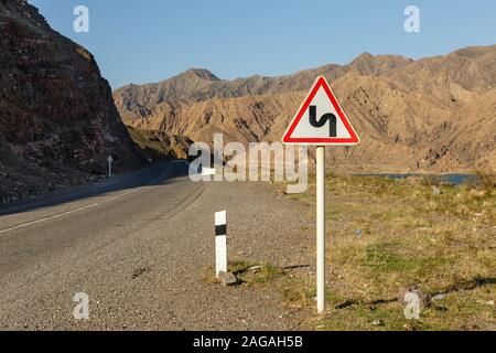 Wicklung zeichen Straße auf einem Mountain Road, Warnung Verkehrsschild Kirgisistan Stockfoto