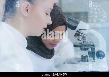 Zwei multiethnischen junge Wissenschaftlerinnen Experimente im Labor. Arbeiten bei lab mit Reagenzgläsern, Test oder Forschung im klinischen Labor. überwachungspersonen Stockfoto