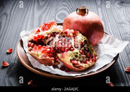 Close-up, reife Granatäpfel auf einem braunen Keramik Schüssel auf einem schwarzen Holztisch Stockfoto