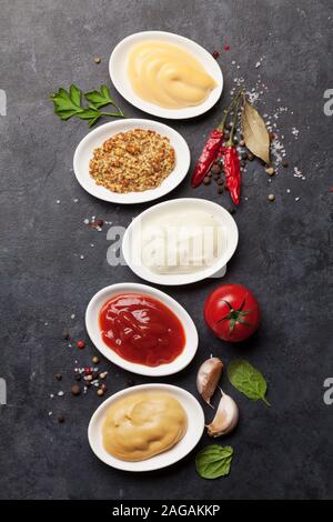 Satz von verschiedenen Saucen. Beliebte Saucen in Schalen - Ketchup, Senf, Mayonnaise. Ansicht von oben. Flach Stockfoto