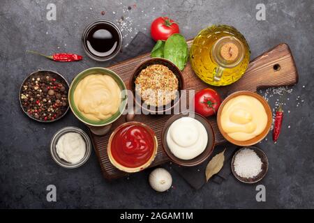 Satz von verschiedenen Saucen. Beliebte Saucen in Schalen - Ketchup, Senf, Mayonnaise. Ansicht von oben. Flach Stockfoto