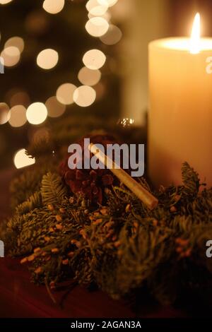 Vertikale Nahaufnahme eines Marihuanas stumpf zwischen Weihnachtsschmuck Und Bokeh Lichter dahinter Stockfoto