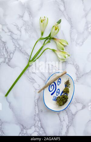 High-Angle-Aufnahme eines Marihuana-Stunts und eines Zweiges Von Blumen auf einer Oberfläche mit schönen Mustern Stockfoto