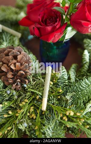 Vertikale Nahaufnahme eines Marihuanas stumpf unter Fichtenleavees Und rote Rosen Stockfoto