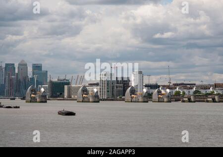 Die Thames Barrier mit Canary Wharf in der Entfernung unter einem bewölkten Himmel, London, England, Vereinigtes Königreich Stockfoto