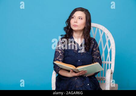 Porträt einer wunderschönen asiatischen Frau in einem dunkelblauen Kleid liest ein Buch Stockfoto