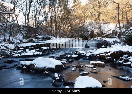 Hebden Wasser (Fluss) strömt durch eine verschneite Wald auf dem Weg abwärts von Hardcastle Crags in Richtung Hebden Bridge. Stockfoto