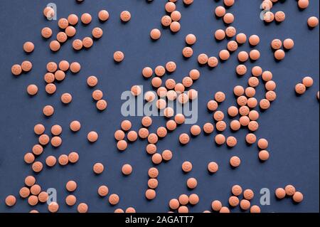 Overhead Schuss von verstreuten kleinen runden Pillen auf einem dunklen Blaue Oberfläche Stockfoto