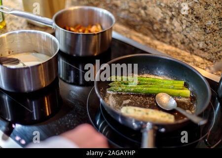 Nahaufnahme des frischen grünen Spargels, der in einem gebraten wird Topf auf einem Gasherd Stockfoto