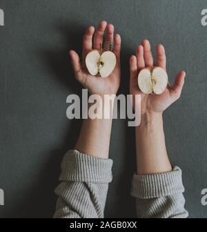 High-Angle-Aufnahme einer Person, die zwei Hälften hält Ein köstlicher frischer Apfel Stockfoto