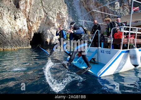 Scuba Diver springen vom Boot im Meer, an der felsigen Küste in Limni Keriou, Zakynthos Insel, Griechenland Stockfoto