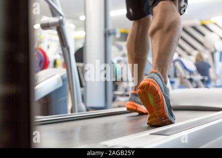 Nahaufnahme der männlichen muskulösen Füße in Turnschuhen auf dem Laufband im Fitnessstudio. Fitness, Workout und gesunden Lebensstil Konzept. Stockfoto
