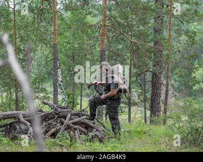 Blick auf ein Jäger in den Wald mit einem Bogen in den Wald führt Moose Hörner auf seinem Rücken. Stockfoto