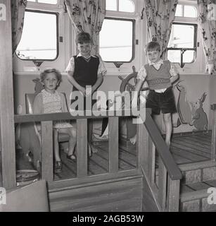 In den 1950er Jahren fuhren auf einem Dampfschiff der Epoche drei junge Kinderpassagiere in der Baumschule. Stockfoto