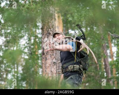 Blick auf ein Jäger in den Wald führt Moose Hörner auf seinem Rücken. Stockfoto