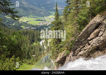 Blick über ein Tal in der Nähe von Krimml, Österreich. Ein Regenbogen ist sichtbar, die von der Gischt des Wasserfalls verursacht. Stockfoto