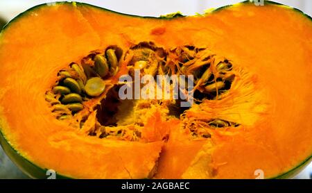 Ein orangefarbener Kürbis, der auf der Küchenoberseite halbiert wurde. Stockfoto