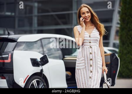 In den Händen. Frau auf der Elektroautos Ladestation bei Tag. Neues Fahrzeug Stockfoto