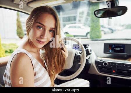 Blickt zurück. Weibliche Fahrer innerhalb des modernen Automobils. Prüfung Nagelneues Auto Stockfoto