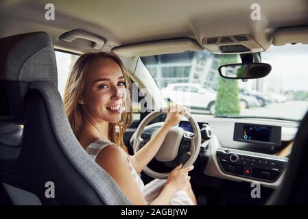 Blickt zurück. Weibliche Fahrer innerhalb des modernen Automobils. Prüfung Nagelneues Auto Stockfoto