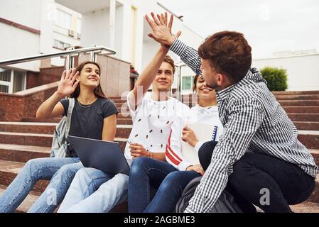 Geben hoch fünf. Gruppe von jungen Studenten in Freizeitkleidung in der Nähe der Universität am Tag Stockfoto