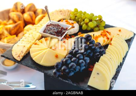 Nahaufnahme von verarbeitetem Käse mit Marmelade und Trauben auf Ein schwarzes Fach Stockfoto