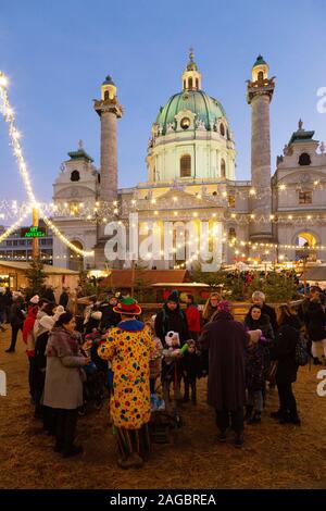 Wiener Weihnachtsmarkt - Menschen auf dem Markt von Karlsplatz vor der St Charles Kirche (Karlskirche), bei Sonnenuntergang, Wien Österreich Europa Stockfoto