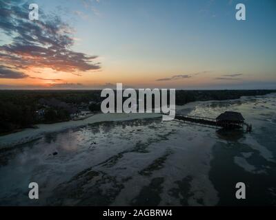 Luftaufnahme eines Piers am Strand am Meer, aufgenommen unter dem Sonnenuntergang in Sansibar, Afrika Stockfoto