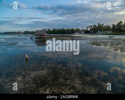 Wunderschöner Pier am ruhigen Meer am Strand unter dem wolkenlosen Himmel, der in Sansibar, Afrika, gefangen ist Stockfoto