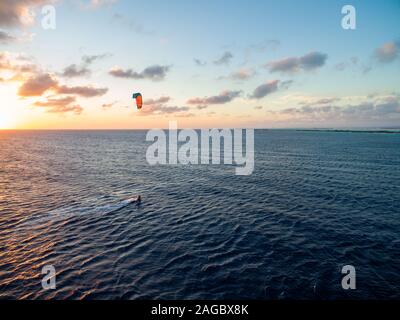 Person, die einen Fallschirm über dem ruhigen Meer während Sonnenaufgang in Kitesurfing fliegt. Bonaire, Karibik Stockfoto