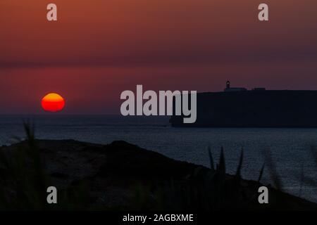 Atemberaubende Aufnahme des Sonnenuntergangs hinter den Wolken über dem ruhigen Meer in Algarve, Portugal Stockfoto