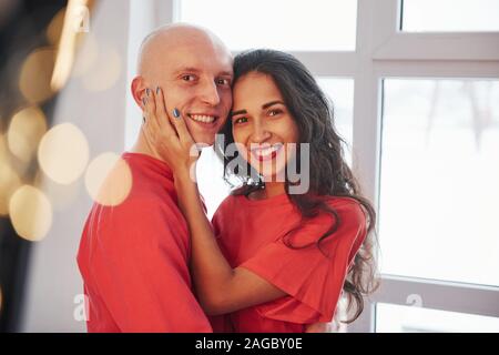 Freundliche Paar stehen in der Nähe der Fenster, lächelnd und schauen in die Kamera Stockfoto