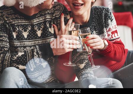 Klopfen Gläser. Gerne jungen Menschen sitzt im Zimmer mit Weihnachtsschmuck Stockfoto