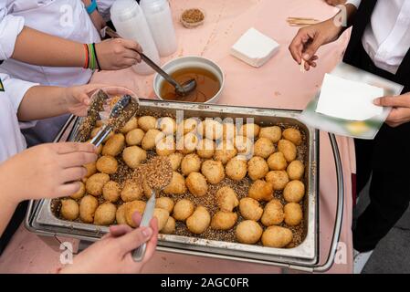 Sweet crispy crunchy Loukoumades berühmten Frittierten griechische traditionelle Gebäck Wüste heiß serviert in Honig getränkt und bestreut mit Zimt und Sesam. Stockfoto