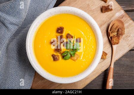 Karotten creme Suppe mit Croutons auf hölzernen Tisch. Ansicht von oben. Gesunde Ernährung Stockfoto
