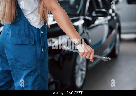 Silhouette von hinten erfasst. Ansicht der Rückseite des weiblichen Reparaturen in der blauen Uniform steht vor der schwarzen Fahrzeug Stockfoto