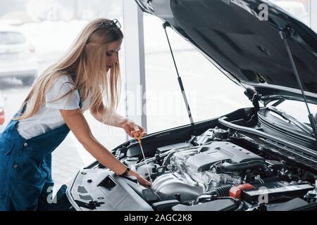 Voll und ganz auf die Arbeit konzentrieren. Auf der schönen Job. Auto süchtig Frau Reparaturen schwarz Automobil im Innenbereich Stockfoto