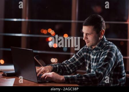 Mann im karierten Hemd haben einige zusätzliche Arbeiten in der Nacht im Büro Stockfoto
