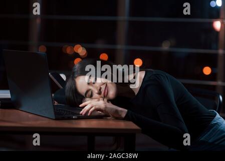 Endlich ausruhen. Attraktive brünette Geschäftsfrau arbeitet allein im Büro bei Nacht Stockfoto