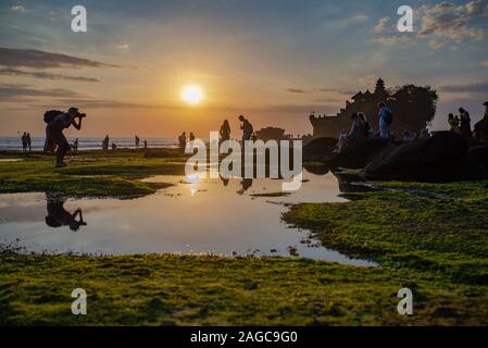 Tanah Lot, Bali, Indonesien, September 7, 2017: Besucher genießen den Sonnenuntergang am Tanah Lot Tempel. Bei Sonnenuntergang mit Reflexion der Himmel und die Menschen i Stockfoto