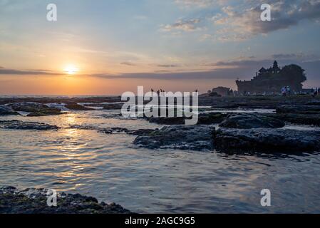 Tanah Lot, Bali, Indonesien, September 7, 2017: Besucher genießen den Sonnenuntergang am Tanah Lot Tempel. Bei Sonnenuntergang mit Reflexion der Himmel und die Menschen i Stockfoto