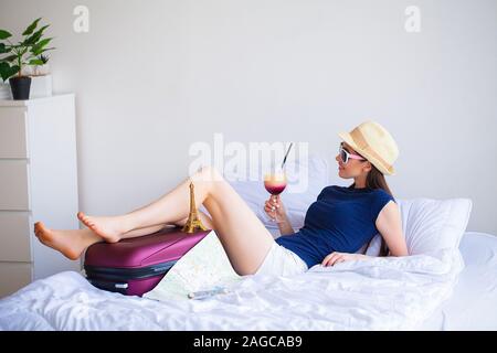 Ferienhäuser. Frau, die Vorbereitung für die Erholung. Junge schöne Mädchen sitzt auf dem Bett. Porträt eines lächelnden Frau. Glückliches Mädchen geht auf Urlaub Stockfoto