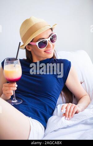 Ferienhäuser. Frau, die Vorbereitung für die Erholung. Junge schöne Mädchen sitzt auf dem Bett. Porträt eines lächelnden Frau. Glückliches Mädchen geht auf Urlaub Stockfoto