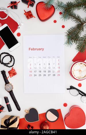 Februar Kalender Seite, Kaffee mit Marshmallow, Smartphone, Tanne, Armbanduhr, Armreifen, Christbaumkugeln, Kosmetik, Armbanduhr auf w isoliert Stockfoto