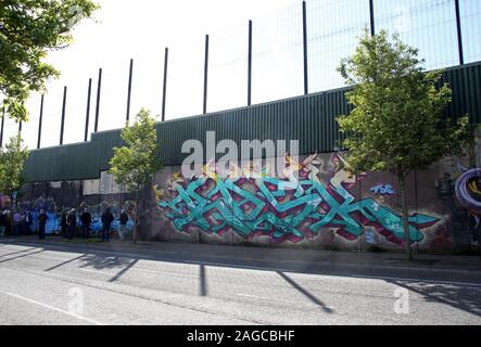Touristen, die farbenfrohen Wandmalereien auf Frieden Wand, oder Frieden Linie, entlang Cupar in Belfast. Es ist eine der Trennung Barrieren in Belfast. Stockfoto