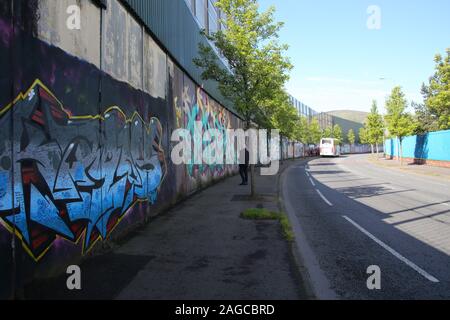 Touristische im Vordergrund und Trainer Partei der Touristen im Hintergrund Blick auf farbenfrohen Wandmalereien und Graffiti auf den Frieden Wand, oder Frieden Line, alo Stockfoto