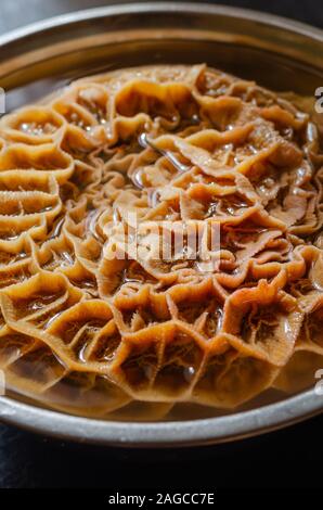 Nahaufnahme einer raw Kuh Magen (Mesh). Frisches Rindfleisch Bauch in eine Schüssel mit Wasser. Close-up. Vertikal. Stockfoto