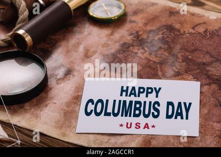 Karte mit glücklichen Columbus Day Inschrift in der Nähe von Kompass und Lupe auf der alten Welt Karte Stockfoto