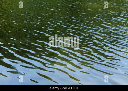 Schöne Aufnahme des dunklen Wassers eines Sees mit Spuren, die durch die sanfte Brise hinterlassen werden Stockfoto