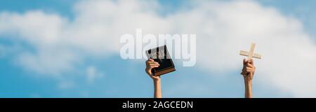 Panorama-aufnahme der Mann mit Bibel und Kreuz gegen den blauen Himmel mit Wolken Stockfoto